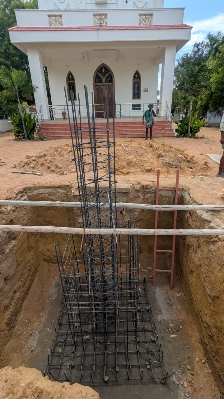 The reinforcement cage seen against the church elevation behind, with the excavation edge barricaded in timber.